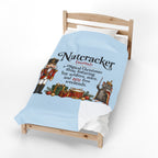 A light blue bedding set, including a duvet cover and matching pillowcases, displayed on a wooden toddler bed. The duvet cover features a printed graphic of a nutcracker and a gray mouse with the text 'Nutcracker (noun): a magical Christmas show featuring toy soldiers, mice, and 200 free weekends.